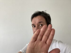 Person zeigt mit der Hand Stopp und verdeckt dabei ihr Gesicht teilweise.